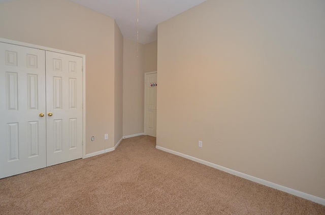 unfurnished bedroom with baseboards, a closet, and light colored carpet