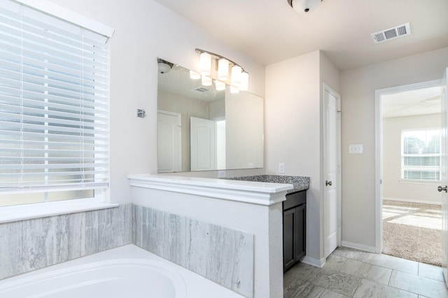 full bathroom featuring a bath, vanity, visible vents, and baseboards