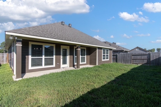 rear view of property with roof with shingles, a lawn, and fence