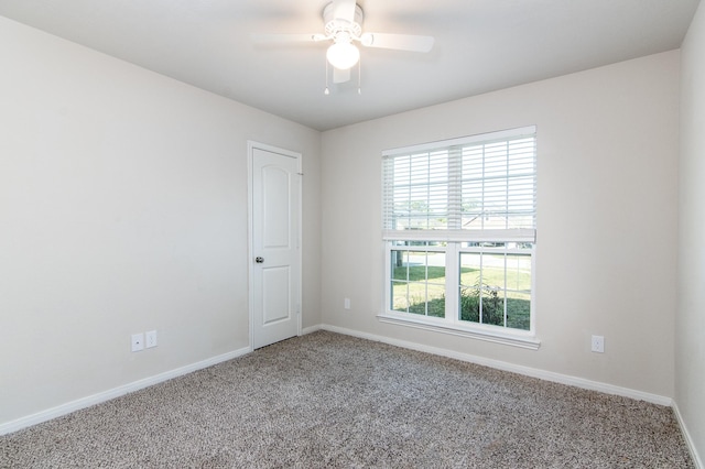 carpeted spare room featuring ceiling fan and baseboards