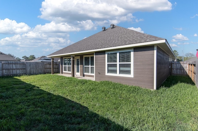 rear view of property with roof with shingles, a lawn, and a fenced backyard