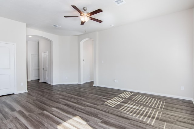 unfurnished room featuring arched walkways, visible vents, ceiling fan, wood finished floors, and baseboards