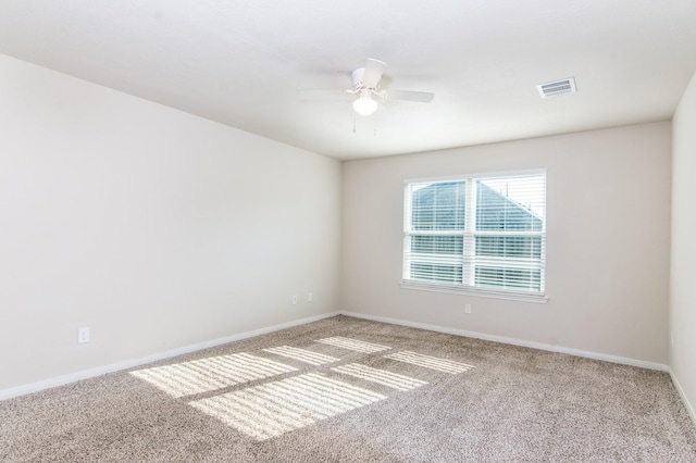 spare room with light colored carpet, visible vents, ceiling fan, and baseboards