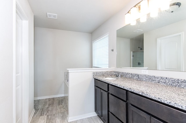 bathroom featuring vanity, visible vents, baseboards, a bath, and a stall shower