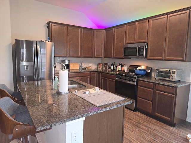 kitchen featuring a toaster, backsplash, appliances with stainless steel finishes, vaulted ceiling, and a sink