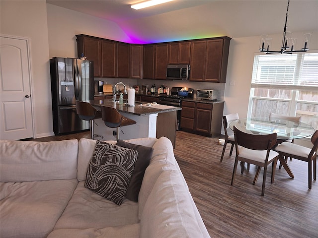 kitchen with stainless steel appliances, dark wood-style flooring, a sink, open floor plan, and vaulted ceiling