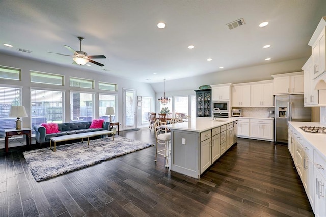 kitchen with sink, a breakfast bar area, appliances with stainless steel finishes, hanging light fixtures, and an island with sink