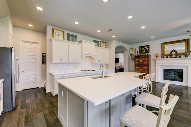 kitchen featuring a breakfast bar, sink, a center island with sink, stainless steel fridge, and white cabinets