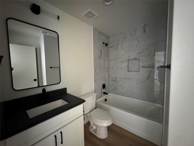 full bathroom with tiled shower / bath, vanity, toilet, and wood-type flooring