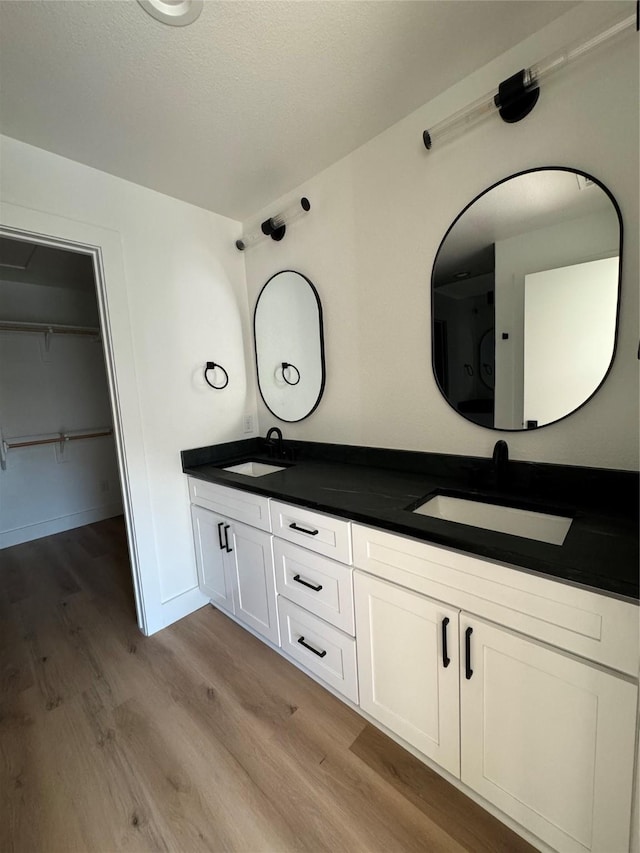 bathroom with wood-type flooring, vanity, and a textured ceiling