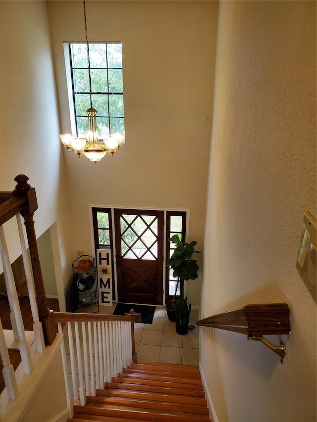 tiled foyer entrance featuring a chandelier and a towering ceiling