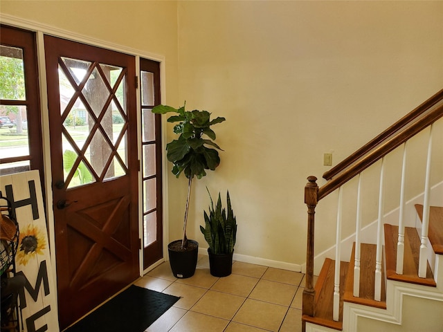 foyer entrance with light tile patterned floors, stairs, and baseboards