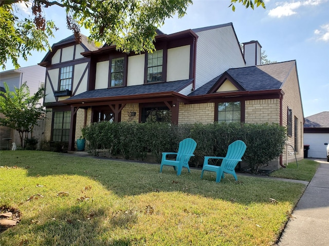 view of front of home with brick siding, roof with shingles, stucco siding, a front lawn, and a chimney