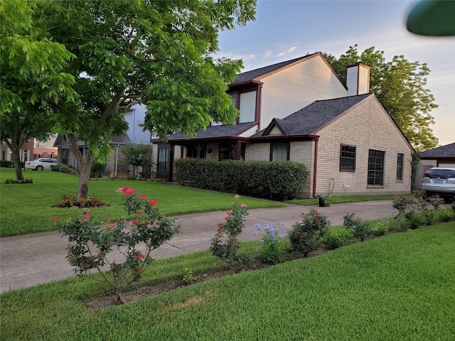 view of home's exterior with a yard, brick siding, a chimney, and a shingled roof