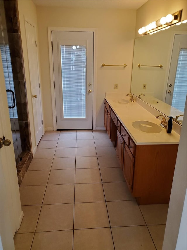 bathroom featuring double vanity, a stall shower, a sink, baseboards, and tile patterned floors