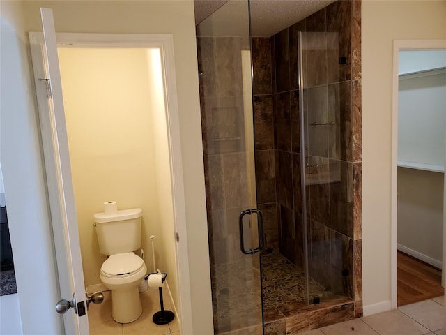 full bathroom with tile patterned flooring, baseboards, a shower stall, and toilet