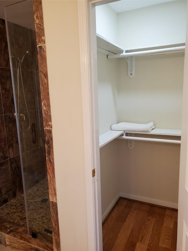 walk in closet with wood finished floors