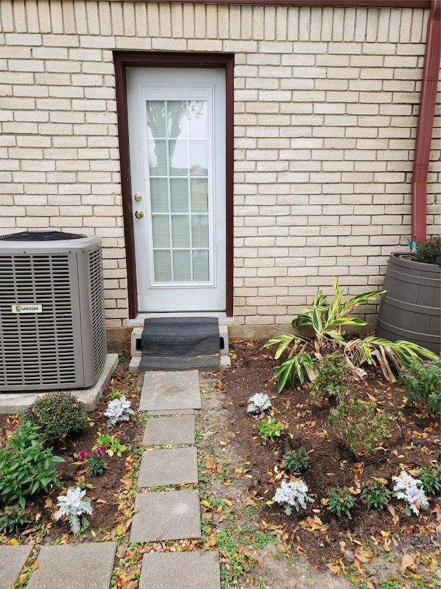 view of exterior entry featuring brick siding and cooling unit