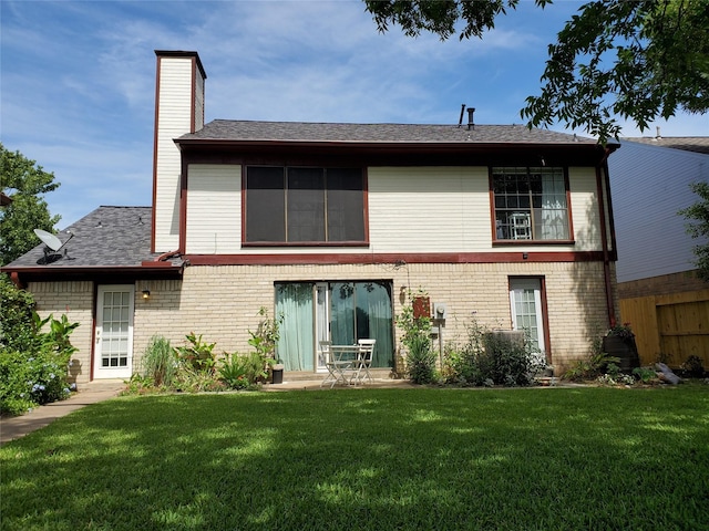 rear view of property with a yard, brick siding, a chimney, and a patio