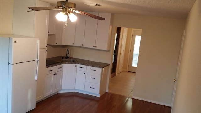 kitchen with freestanding refrigerator, dark wood finished floors, a sink, and dark countertops