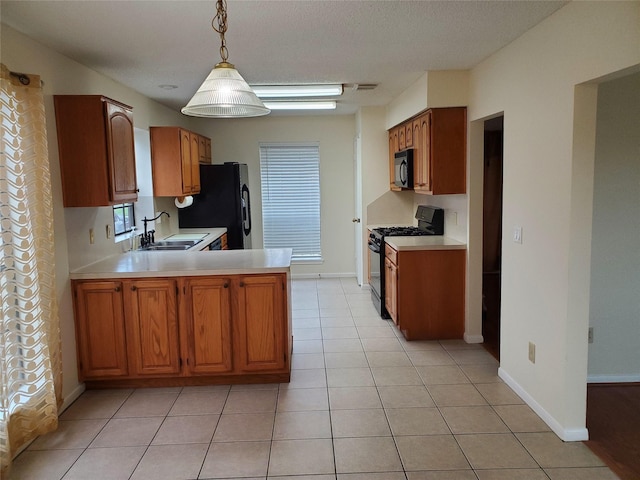 kitchen featuring a peninsula, light countertops, black appliances, a sink, and light tile patterned flooring