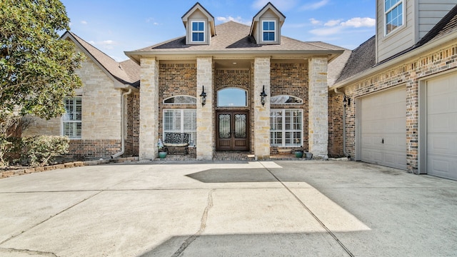 view of front of home with driveway, brick siding, stone siding, and french doors