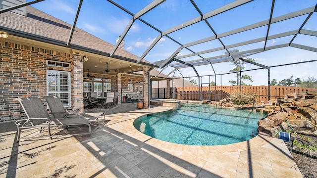 view of swimming pool with a pool with connected hot tub, a patio area, fence, ceiling fan, and a lanai