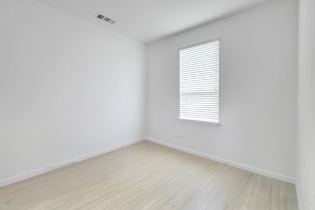 unfurnished room featuring visible vents, light wood-style flooring, and baseboards