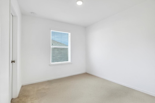 empty room featuring baseboards and light colored carpet