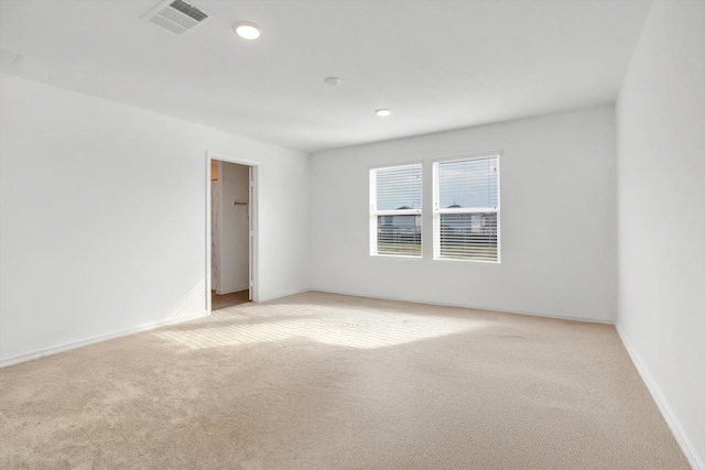 empty room featuring baseboards, visible vents, and light colored carpet