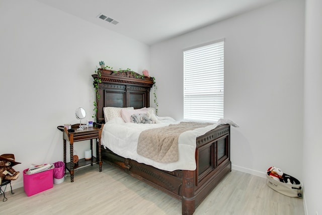 bedroom with visible vents, baseboards, and wood finished floors