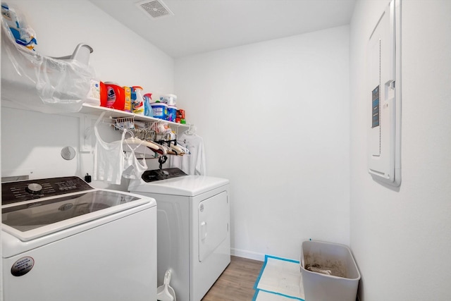 clothes washing area with laundry area, visible vents, baseboards, light wood-style floors, and washer and dryer