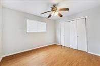 unfurnished bedroom featuring ceiling fan, wood-type flooring, and a closet