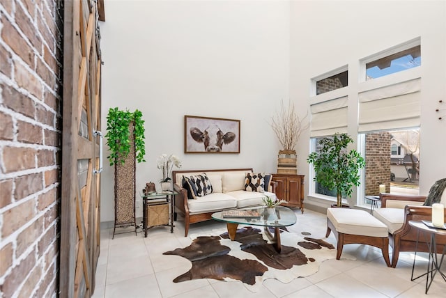 sitting room featuring a towering ceiling, brick wall, and light tile patterned floors