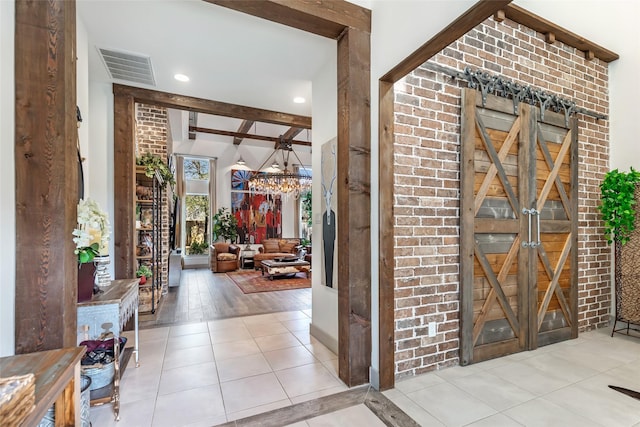 entryway featuring a notable chandelier, brick wall, beamed ceiling, and light tile patterned flooring