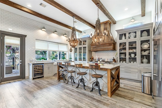 kitchen featuring wine cooler, light hardwood / wood-style floors, a center island, and a healthy amount of sunlight