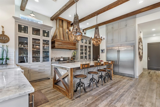 kitchen featuring gray cabinets, stainless steel built in refrigerator, pendant lighting, and light stone counters