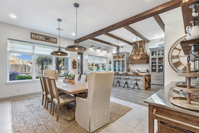 tiled dining space featuring beam ceiling