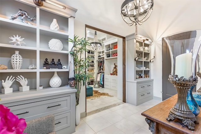 walk in closet with light tile patterned floors and an inviting chandelier