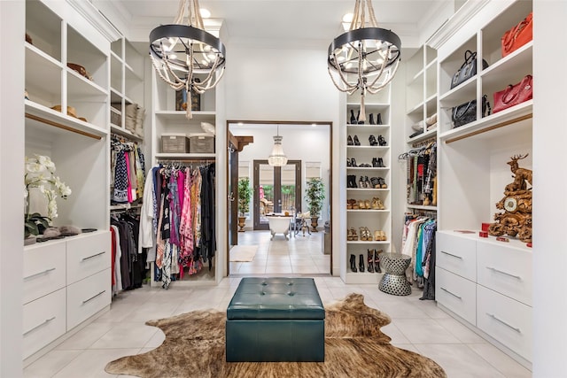 spacious closet featuring french doors, a chandelier, and light tile patterned floors