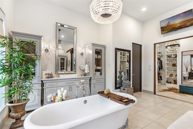 bathroom featuring vanity, a bath, a notable chandelier, tile patterned flooring, and a high ceiling