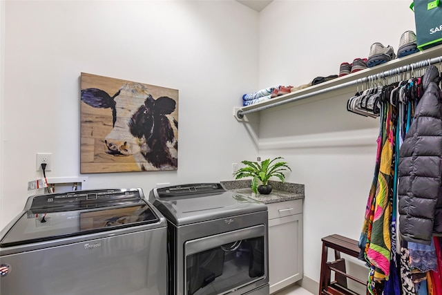 clothes washing area featuring cabinets and washing machine and clothes dryer