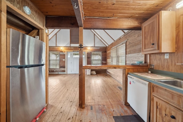 kitchen featuring wooden walls, vaulted ceiling with beams, stainless steel fridge, and white dishwasher