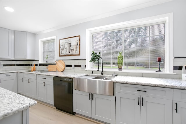 kitchen featuring plenty of natural light, black dishwasher, a sink, and backsplash