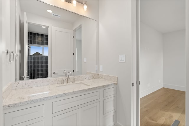 bathroom with baseboards, visible vents, wood finished floors, and vanity