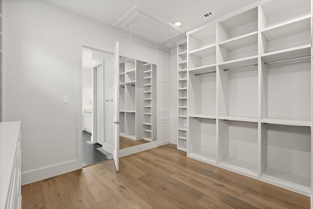 spacious closet with visible vents, wood finished floors, and attic access