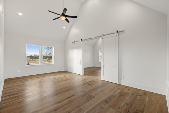 11585 Grandview Dr, Montgomery, TX 77356 - unfurnished bedroom featuring a barn door, high vaulted ceiling, recessed lighting, baseboards, and wood finished floors