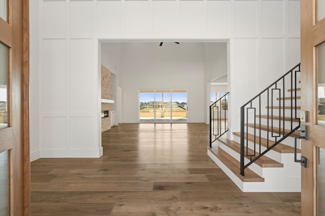 foyer entrance with stairs, a fireplace, wood finished floors, and a decorative wall