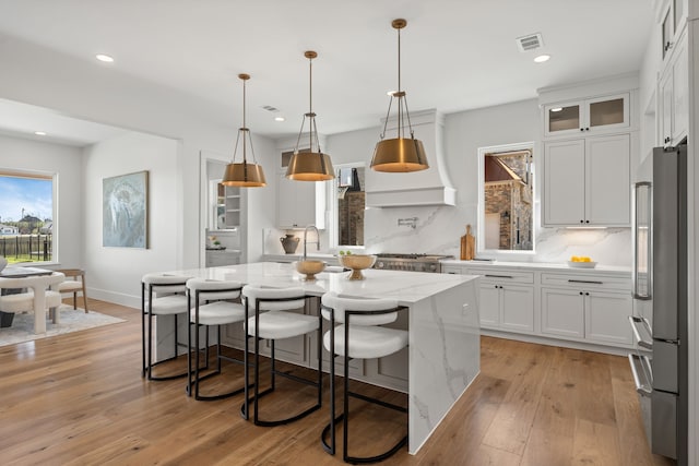 11585 Grandview Dr, Montgomery, TX 77356 - kitchen with high end refrigerator, white cabinets, light stone counters, decorative backsplash, and an island with sink
