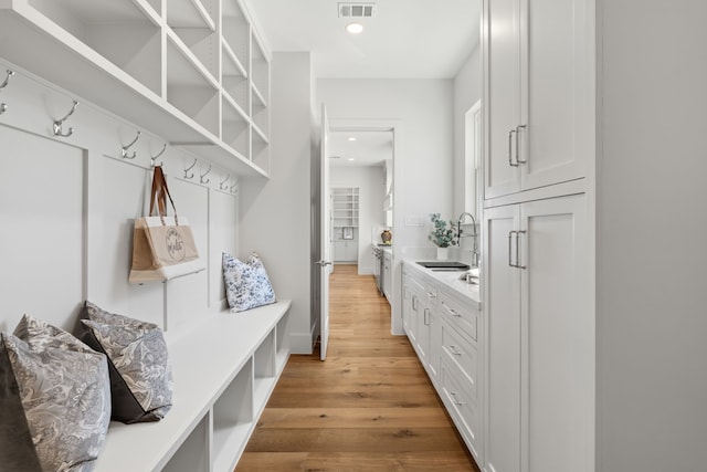 mudroom featuring light wood-type flooring, visible vents, a sink, and recessed lighting